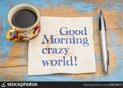Good Morning crazy world - handwriting on a napkin with a cup of espresso coffee