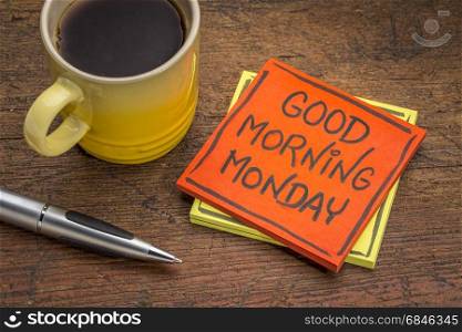 Good morning Monday - cheerful message on a sticky note with a cup of coffee and pen