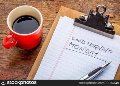 Good morning, Monday - handwriting on a small clipboard with a cup of coffee