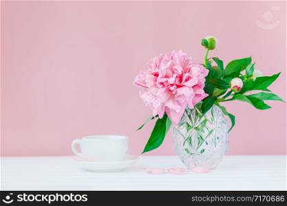 Good morning. Pink peonies in a crystal vase on a pink wood background, copy space, close up.. Pink peonies in a crystal vase on a pink wood background.
