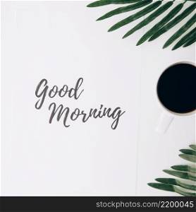 good morning text paper with coffee cup leaves against white background