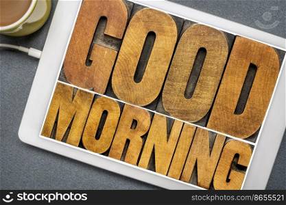 Good Morning word abstract - text in vintage letterpress wood type printing blocks on a digital tablet with a cup of coffee