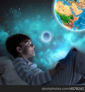 Good night. Boy sitting in bed and dreaming. Elements of this image are furnished by NASA