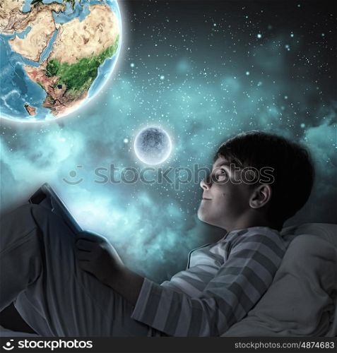 Good night. Boy sitting in bed and dreaming. Elements of this image are furnished by NASA