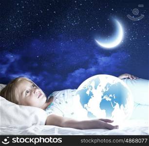Good night. Girl in bed with Earth planet in hands