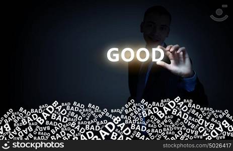 Good or bad concept. Businessman on dark background taking with fingers glowing word good