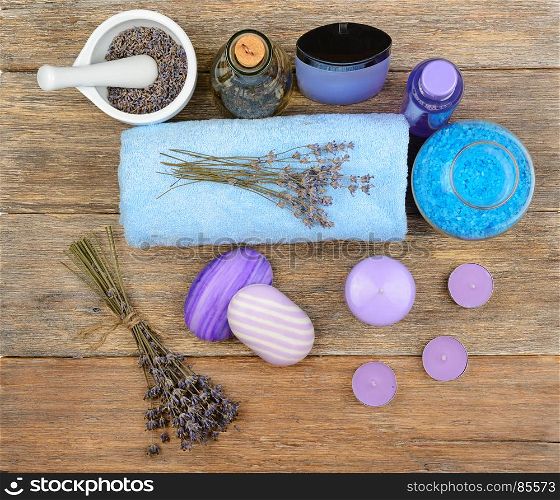 Goods for spa: soap, sea salt, towel, oil of lavender on wooden table. top view