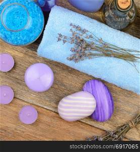 Goods for the spa: soap, sea salt, towel, oil of lavender on wooden table. top view