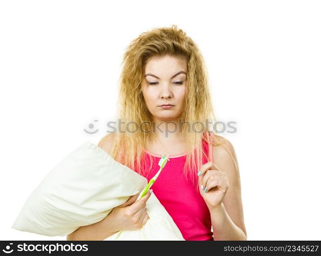 Goofy blonde woman holding toothbrush and pillow, having morning wake up trouble after big bad night.. Goofy woman having morning bad mood