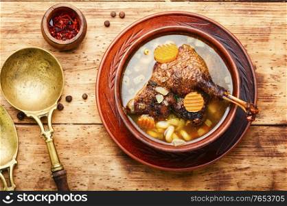 Goose soup with vegetables and pasta. A bowl of duck soup on wooden table. Appetizing goose soup