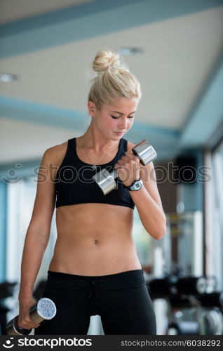 Gorgeou woman girl lifting some weights and working on her biceps in a gym