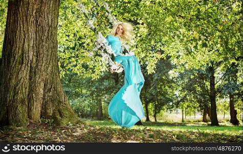Gorgeous blond lady on a flower seesaw in a park