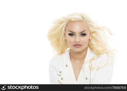 Gorgeous blond woman with her long hair blowing in a breeze in a stylish white blouse gazing at the camera with a serious expression, isolated on white