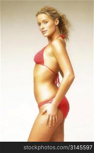Gorgeous blonde woman poses in a red bikini in the studio.