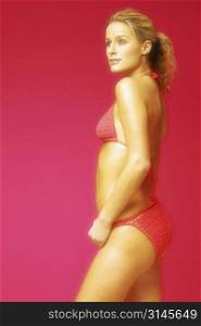 Gorgeous blonde woman poses in a red bikini in the studio.