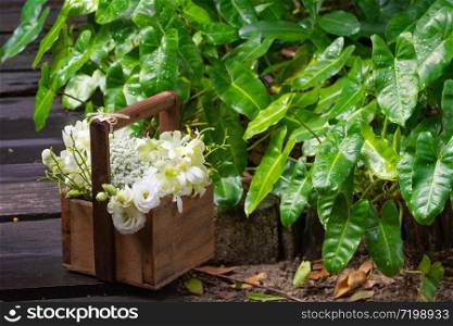 Gorgeous bridal wedding bouquet of white roses, hydrangeas, ozotamnusa,eucalyptus and orchid in wood basket on beautiful concrete path with green left background