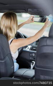 gorgeous brunette fixing up rearview car mirror