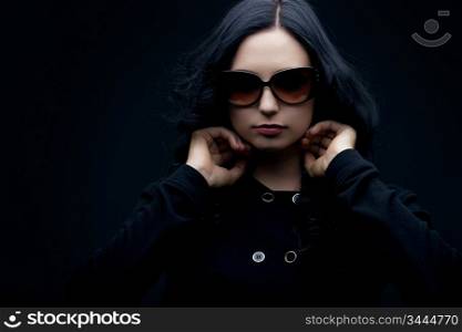 gorgeous brunette wearing sunglasses posing in the studio, low key