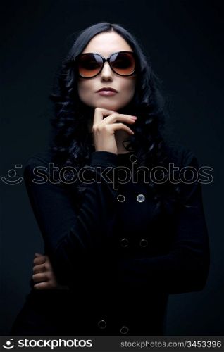 gorgeous brunette wearing sunglasses posing in the studio, low key