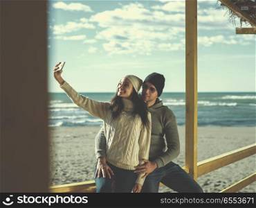 Gorgeous couple taking Selfie picture. Very Happy Couple In Love Taking Selfie On The Beach in autmun day colored filter