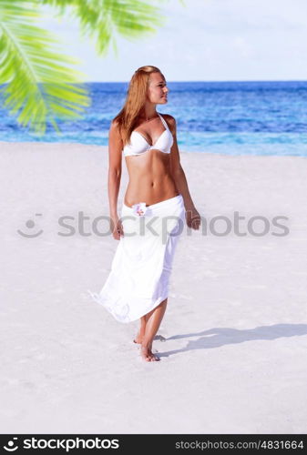 Gorgeous female having fun on the beach, walking on sandy seashore, spending summer holidays on Maldives island, travel and tourism concept