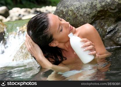 Gorgeous girl in river applying hair conditioner