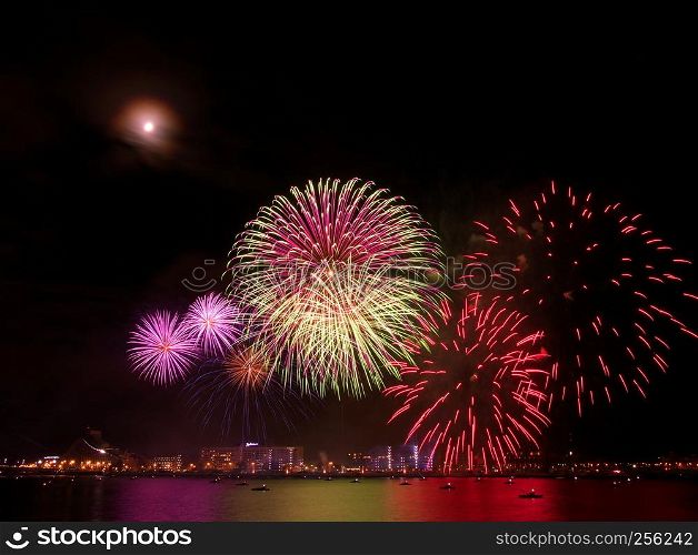 Gorgeous multi-colored light show and fireworks display on dark night sky over the river