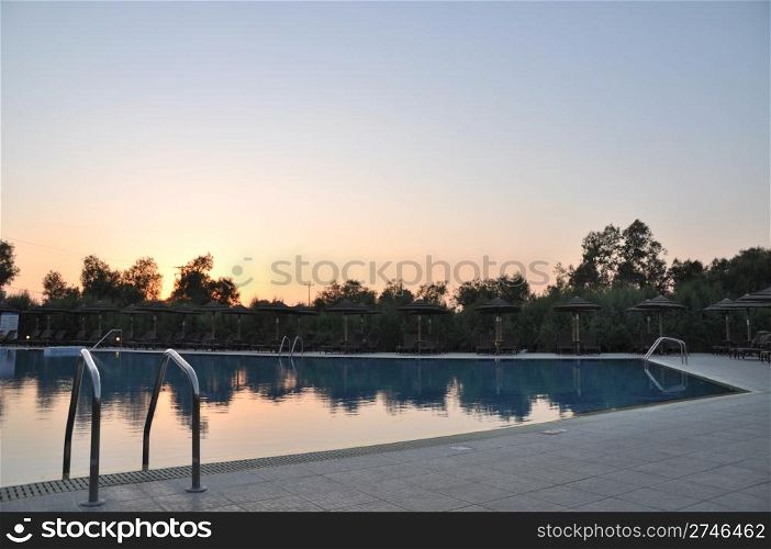 gorgeous resort swimming pool with umbrellas during sunset