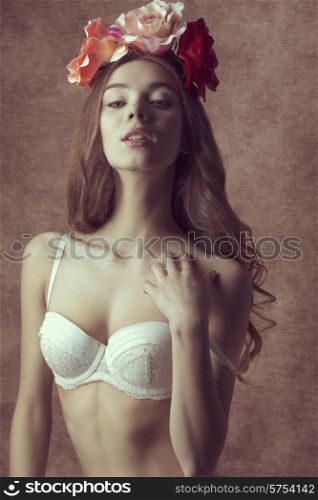 Gorgeous, romantic, spring, brunette woman with flowers on the head, white bra and nude make up.