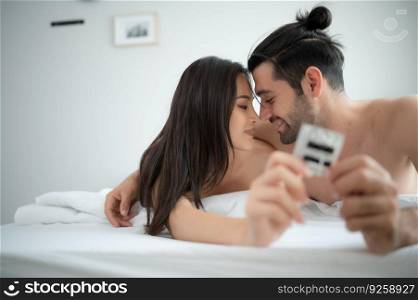 Gorgeous sexy couple enjoying sex in the house’s bedroom, Safe sex concept, couples with condoms.
