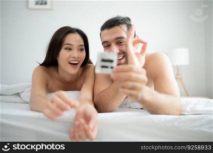 Gorgeous sexy couple enjoying sex in the house’s bedroom, Safe sex concept, couples with condoms.