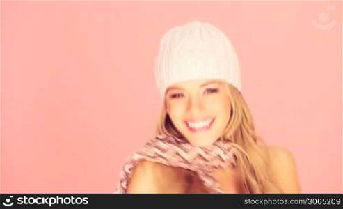 Gorgeous smiling happy blonde woman in a knitted winter cap and scarf with bare shoulders.