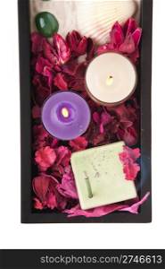 gorgeous spa setting with candles, stones, sand, incense, seashell and dry petal roses and other flowers on a black tray (close-up picture isolated on white background)