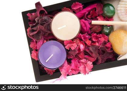 gorgeous spa setting with candles, stones, sand, seashells, rake, dry petal roses and other flowers on a black tray (close up picture isolated on white background)