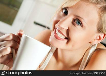 Gorgeous woman visibly enjoying a hot cup of coffee in the morning