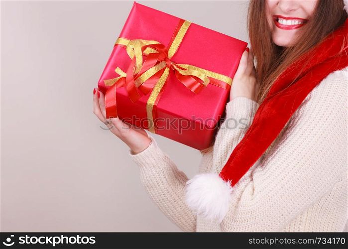 Gorgeous woman wearing santa claus hat holding red big gift box with ribbon. Xmas, happiness, winter and people concept.. Woman holding gift box. Christmas time