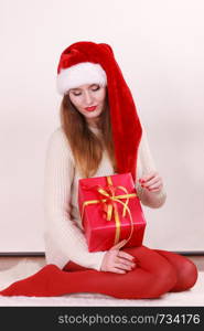 Gorgeous woman wearing santa claus hat holding red big gift box with ribbon. Xmas, happiness, winter and people concept.. Woman holding gift box. Christmas time