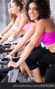 Gorgeous young females cycling in spinning class in gym.