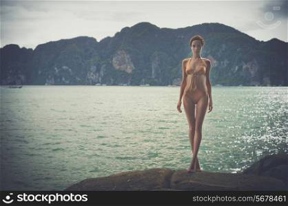 Gorgeous young lady in a golden swimsuit at the sea
