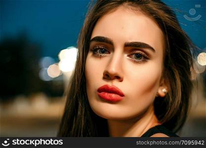Gorgeous young model woman looking at camera posing in the city wearing black evening dress.