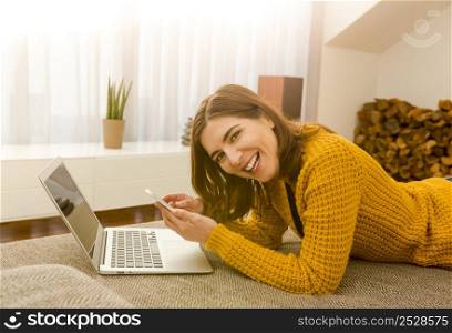 Gorgeous young woman at home texting and laughing