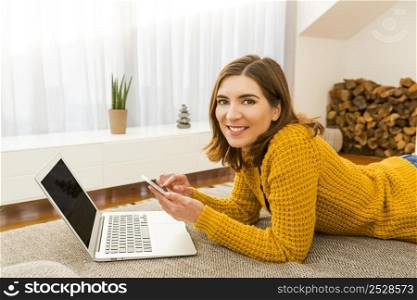 Gorgeous young woman at home working with a laptop and texting