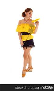 Gorgeous young woman in a yellow blouse and black shorts holding one sunflower, standing isolated for white background.