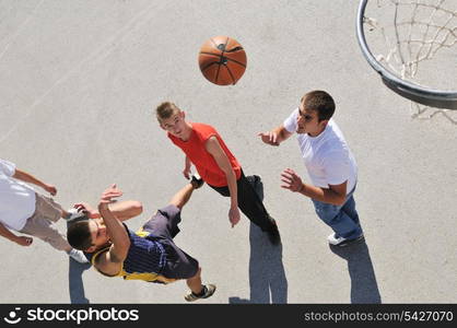 gorup of young boys who playing basketball outdoor on street with long shadows and bird view perspective