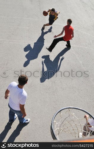 gorup of young boys who playing basketball outdoor on street with long shadows and bird view perspective