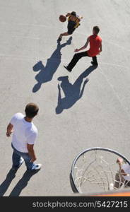 gorup of young boys who playing basketball outdoor on street with long shadows and bird view perspective