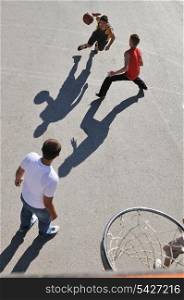 gorup of young boys who playing basketball outdoor on street with long shadows and bird view perspective