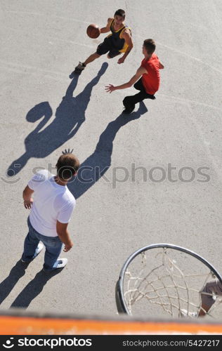 gorup of young boys who playing basketball outdoor on street with long shadows and bird view perspective