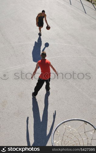 gorup of young boys who playing basketball outdoor on street with long shadows and bird view perspective