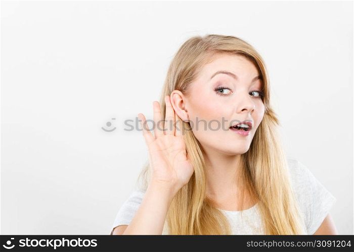 Gossip,rumors, whisper, hearing concept. Young blonde Woman putting hand ear to hear better. Studio shot on white background.. Woman putting hand ear to hear better
